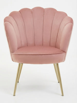 The Petal Chair features blush pink velvet upholstery, a scalloped shell-like backrest, and gold tapered metal legs, shown against a plain white background.