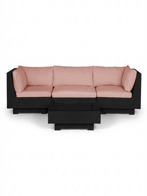 The Sereno Black modular outdoor rattan sofa with light pink cushions is arranged in an L-shape beside a matching low rectangular coffee table, forming a contemporary set against a plain white background.
