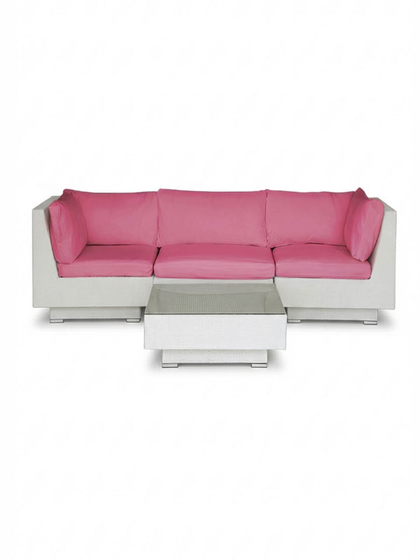 The Sereno White modular sofa features bright pink cushions and an L-shaped design, paired with a matching low rectangular white coffee table—ideal as stylish outdoor lounge furniture.