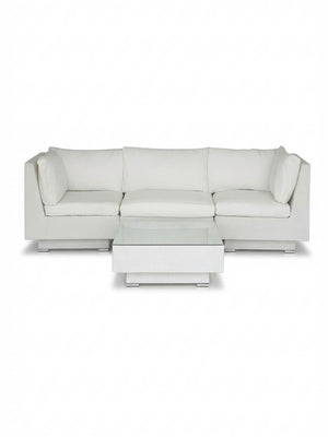 The Sereno White features a modern modular white sectional sofa with clean lines and plush cushions, plus a matching square coffee table—all set against a plain white background for stylish outdoor lounging.