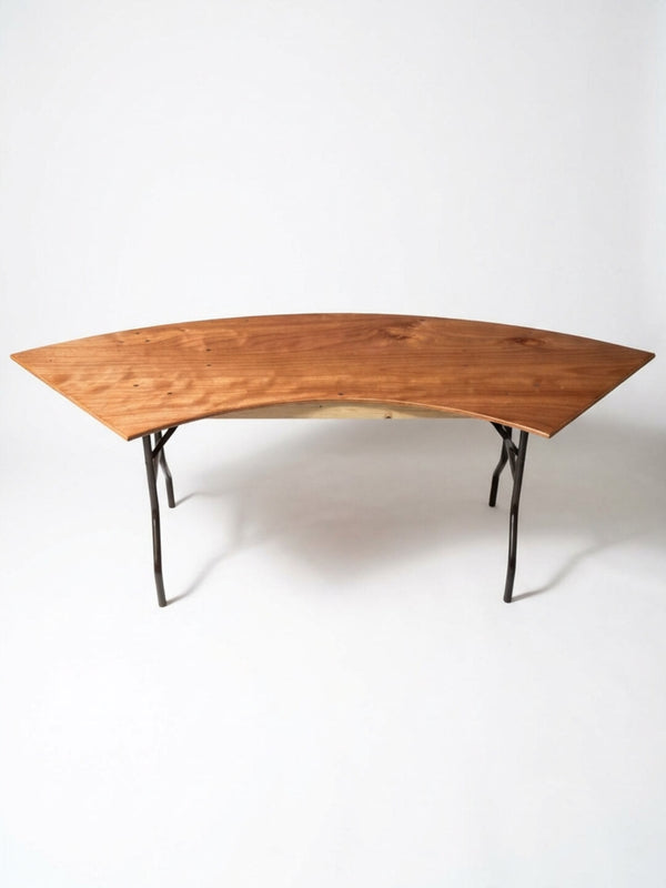 The Serpentine Table features a modern, curved design with a smooth natural finish and angled metal legs, shown against a plain white background.