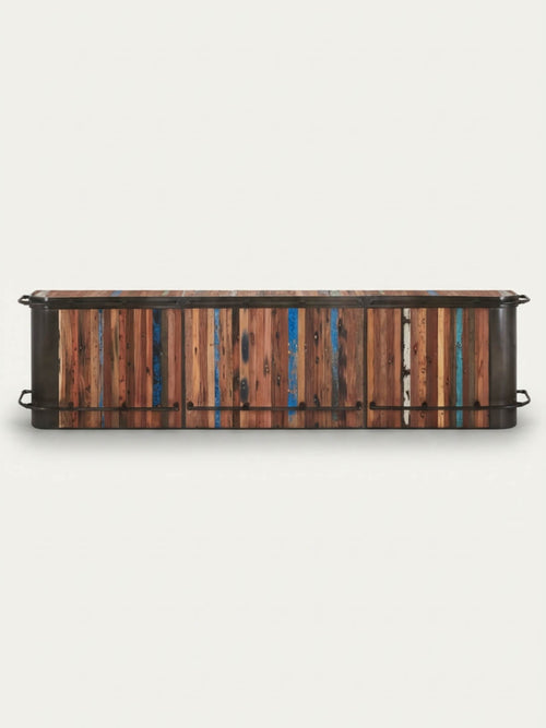 The Urban Wood Bar is a low, rectangular reclaimed wood cabinet with multicolored vertical slats in brown, blue, and teal, plus black metal handles on each side. Shown against a plain white background.