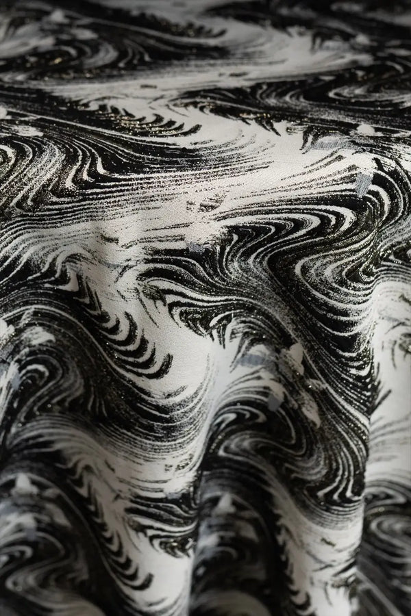 Table linen with swirling abstract motifs with shimmering gold thread add dynamic elegance to luxurious tablescapes.
