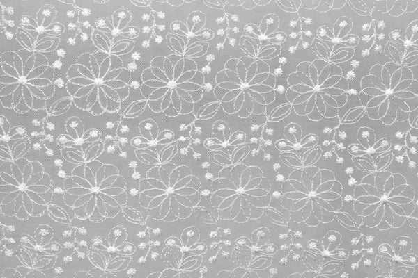 Table linen with floral embroidery overlay adding playful elegance, enhancing tables with delicate florals.