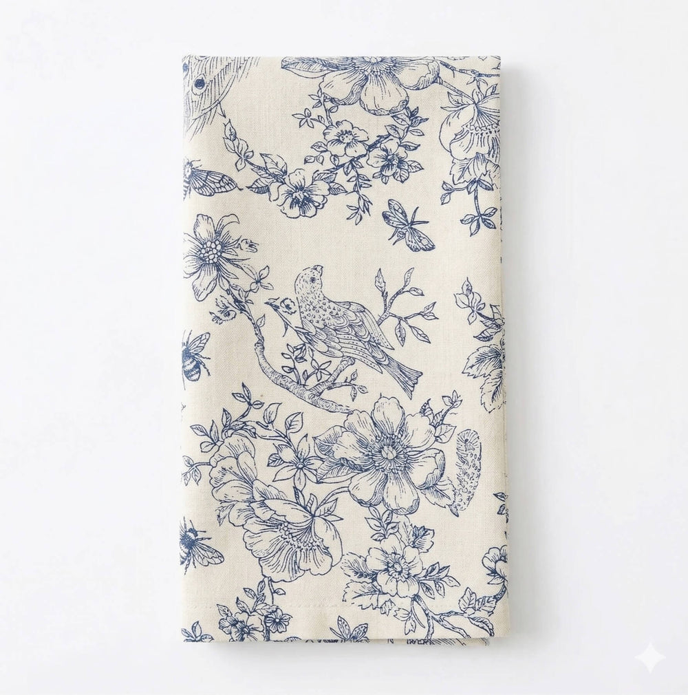 A close-up of the Chatsworth Linen Sample shows blue floral and bird motifs, leaf details, and a dragonfly on a light beige background—ideal for adding elegance to any event setting.