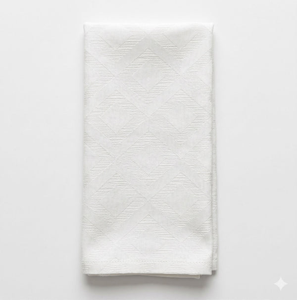 A neatly folded white cloth napkin with a subtle geometric pattern from Dali Linen, shown on a white background, captures modern sophistication.