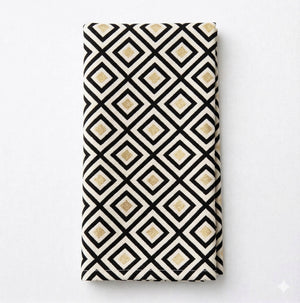 The Hera Linen napkin features a geometric black diamond pattern outlined in white with gold square accents on a white background—ideal for modern event decor and pairing with black and gold linens.