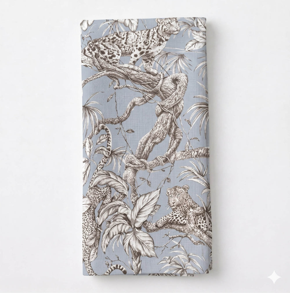 Leonard Dove Linen features a soft grey-blue shade with an intricate print of tree branches, leaves, and subtle leopard and jungle motifs, elegantly draped in premium linen.