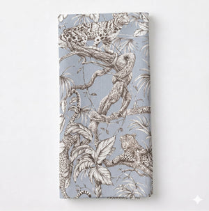 A folded Leonard Dove Linen in grey-blue, showcasing detailed black-and-white leopard and jungle motifs on a light blue background.