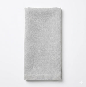 A neatly folded Nova Linen napkin in light gray rests on a white background, highlighting its minimalist elegance for any event.