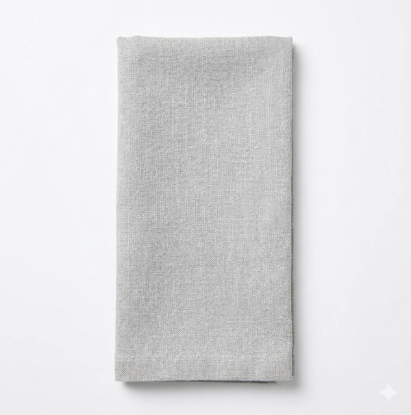 A neatly folded Nova Linen napkin in light gray rests on a white background, highlighting its minimalist elegance for any event.