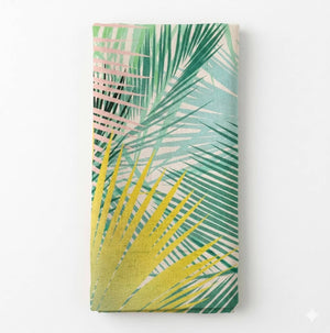 Sienna Linen is a folded fabric with a tropical palm leaf pattern in green, yellow, and light pink shades on a light background.