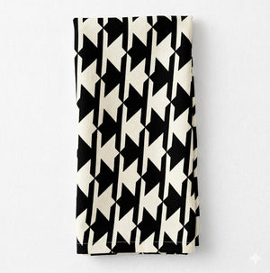 The Stella Linen napkin, showcasing a bold black and white houndstooth pattern, is neatly folded and displayed on a plain white background.