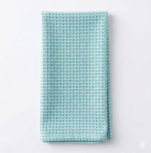 A neatly folded Waffle Duck Egg Linen towel with a textured waffle pattern is displayed on a plain white background.