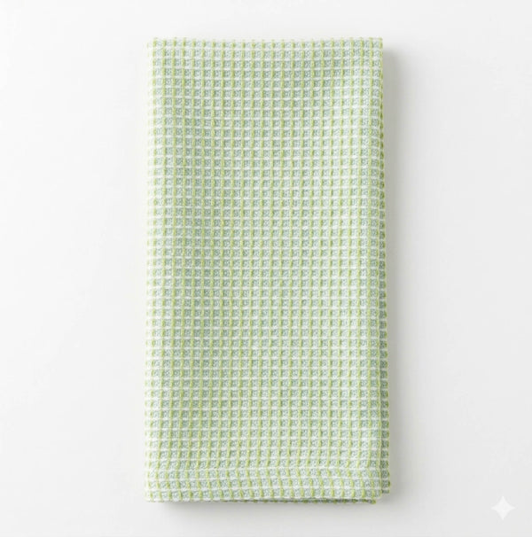 The Waffle Green Linen towel, featuring a unique waffle pattern and soft light green linen, is neatly folded on a plain white background.