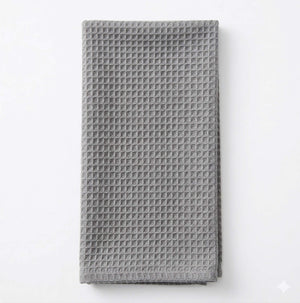 The Waffle Light Grey Linen kitchen towel is folded and laid flat on a white background, offering subtle elegance to any event setting.
