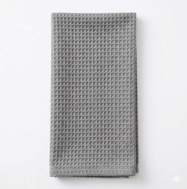 The Waffle Light Grey Linen kitchen towel is folded and laid flat on a white background, offering subtle elegance to any event setting.
