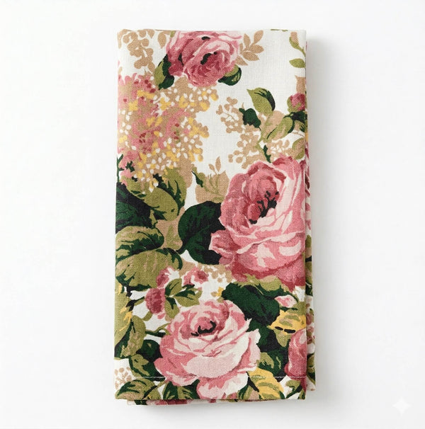 The Zara Linen folded cloth napkin features a vintage floral pattern with pink roses, green leaves, and beige accents on a white background—ideal for elegant event decor.